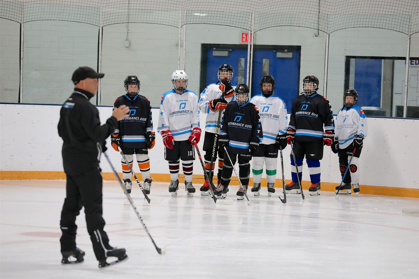 A coach running a skills session with youth hockey players